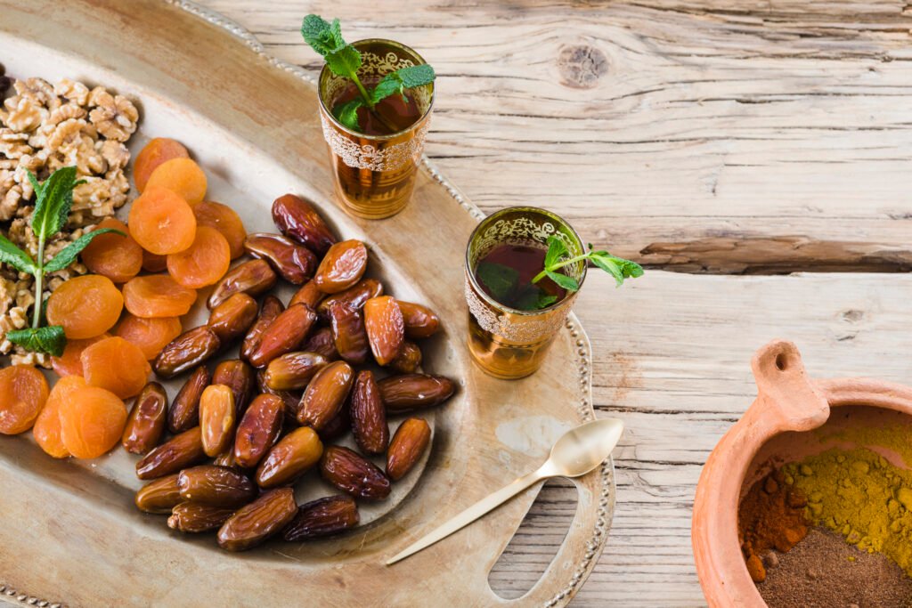 cups with plant twigs near bowl with spices dried fruits nuts tray